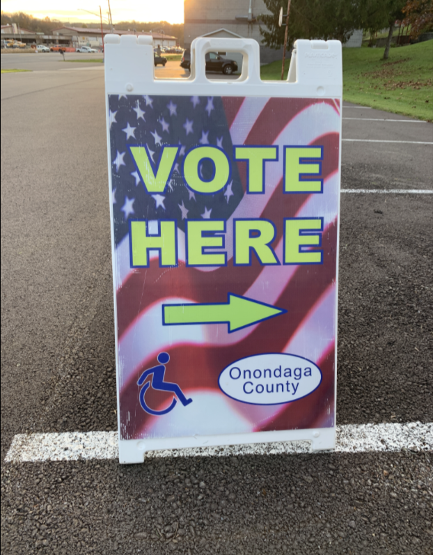American Flag poster says "vote here" with an arrow pointing to the right.