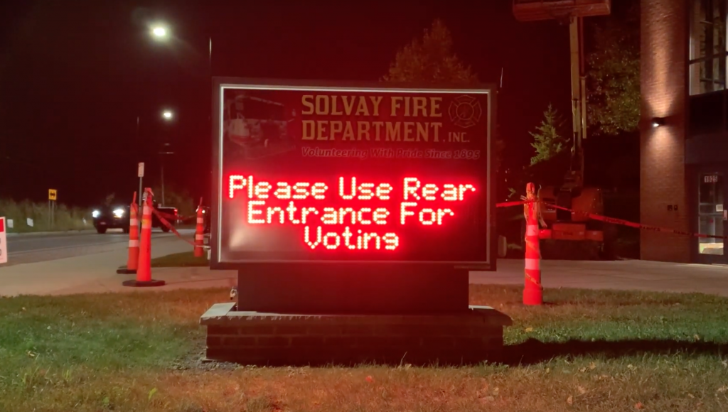 A sign at the Solvay Fire Department telling voters to "Please use rear entrance for voting," in red lights.
