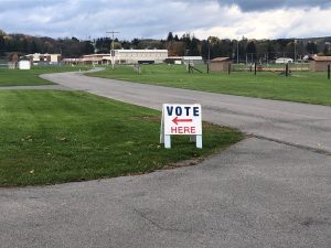 A sign directs voters towards a building with a red arrow.