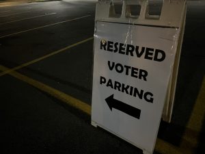 Le Moyne parking sign pointing towards voting center on campus.